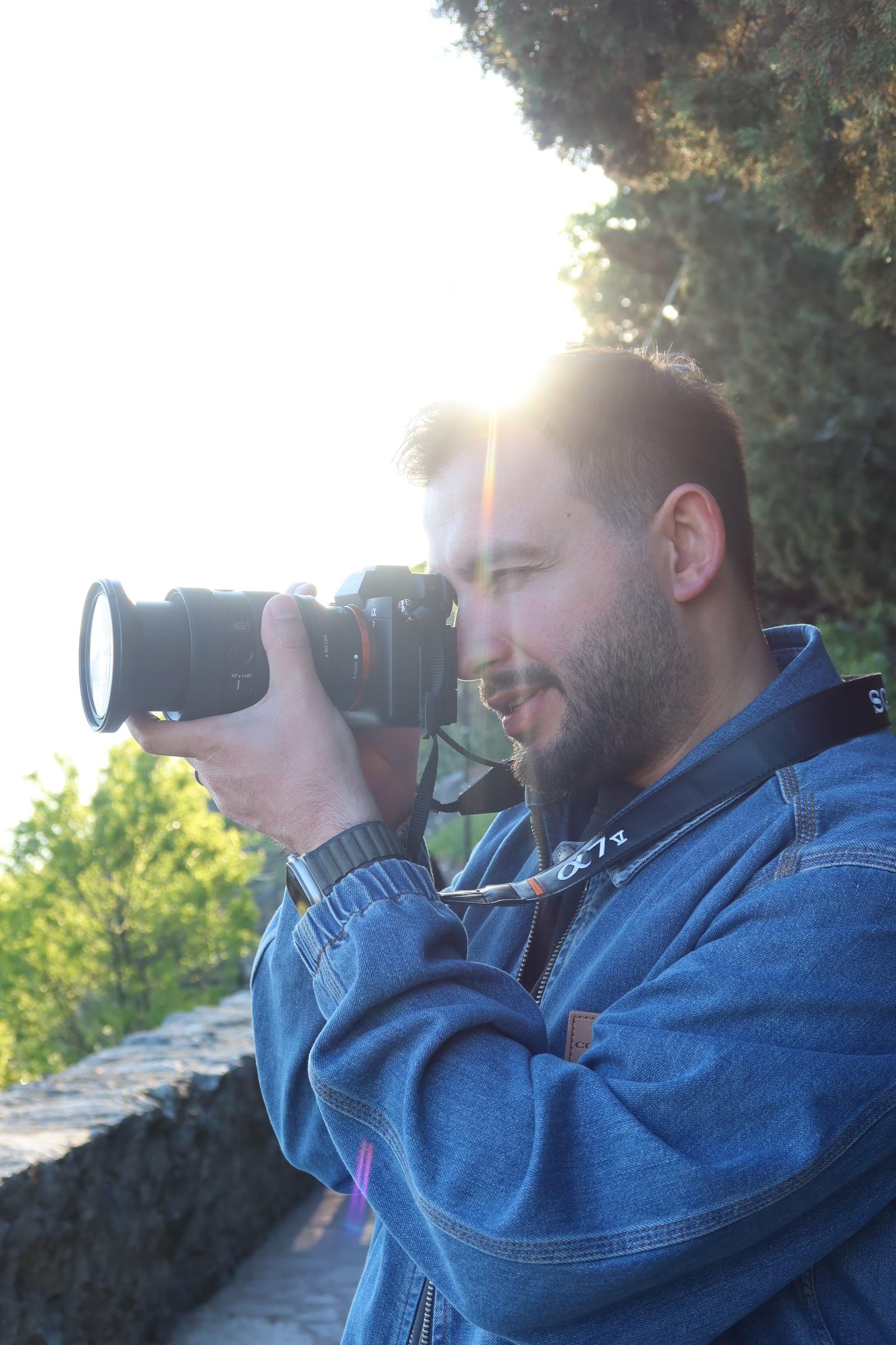 Tuncay Aydın photographing in warm evening light, camera raised to the eye